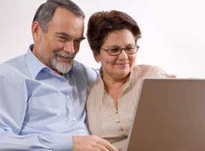 Couple de retraités souriants devant leur ordinateur portable